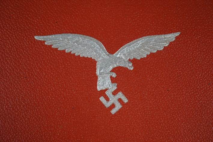 A white eagle with a swastika symbol on a red surface

Description automatically generated