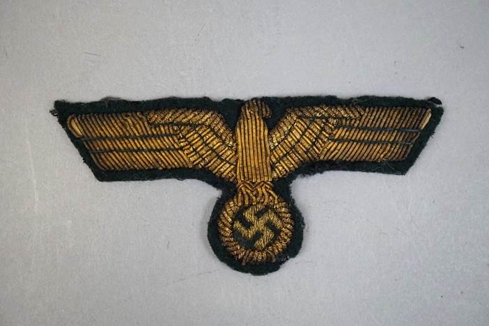 A gold eagle patch with a swastika

Description automatically generated